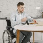 Mężczyzna na wózku inwalidzkim naprawia sprzęt AGD w kuchni