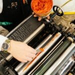Osoba nakłada farbę na zabytkową maszynę drukarską Heidelberg