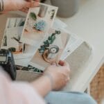 Osoba przegląda wydruki zdjęć rozłożone na białym stole