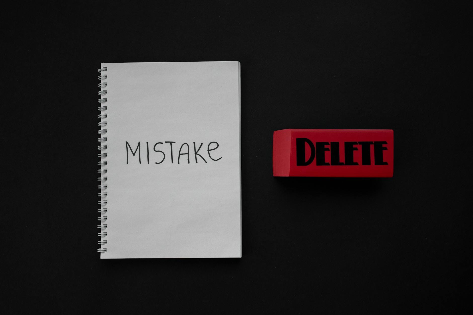 Zeszyt z napisem Mistake i czerwona gumka do mazania na ciemnym tle