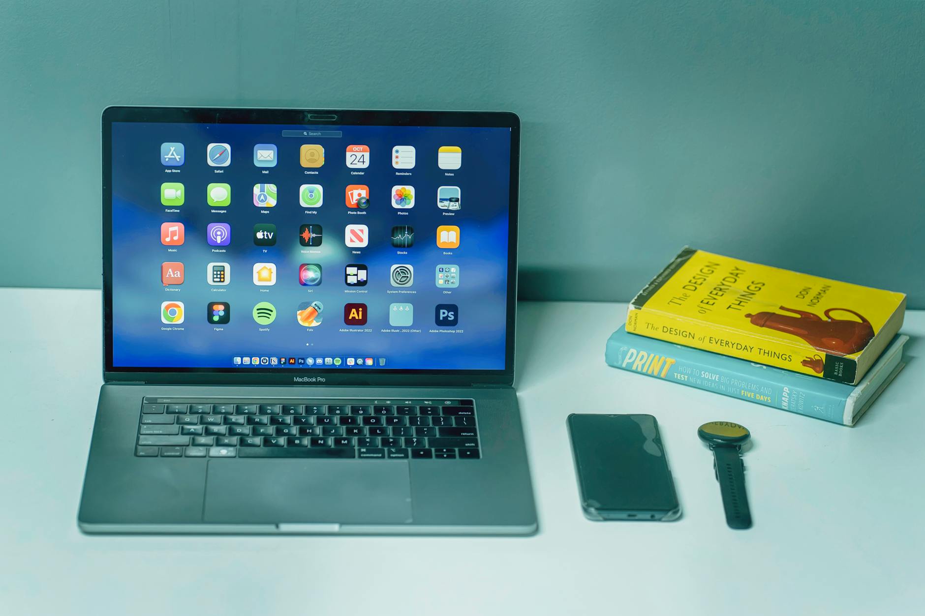 Biurko z laptopem, smartfonem, zegarkiem i książkami w nowoczesnym biurze