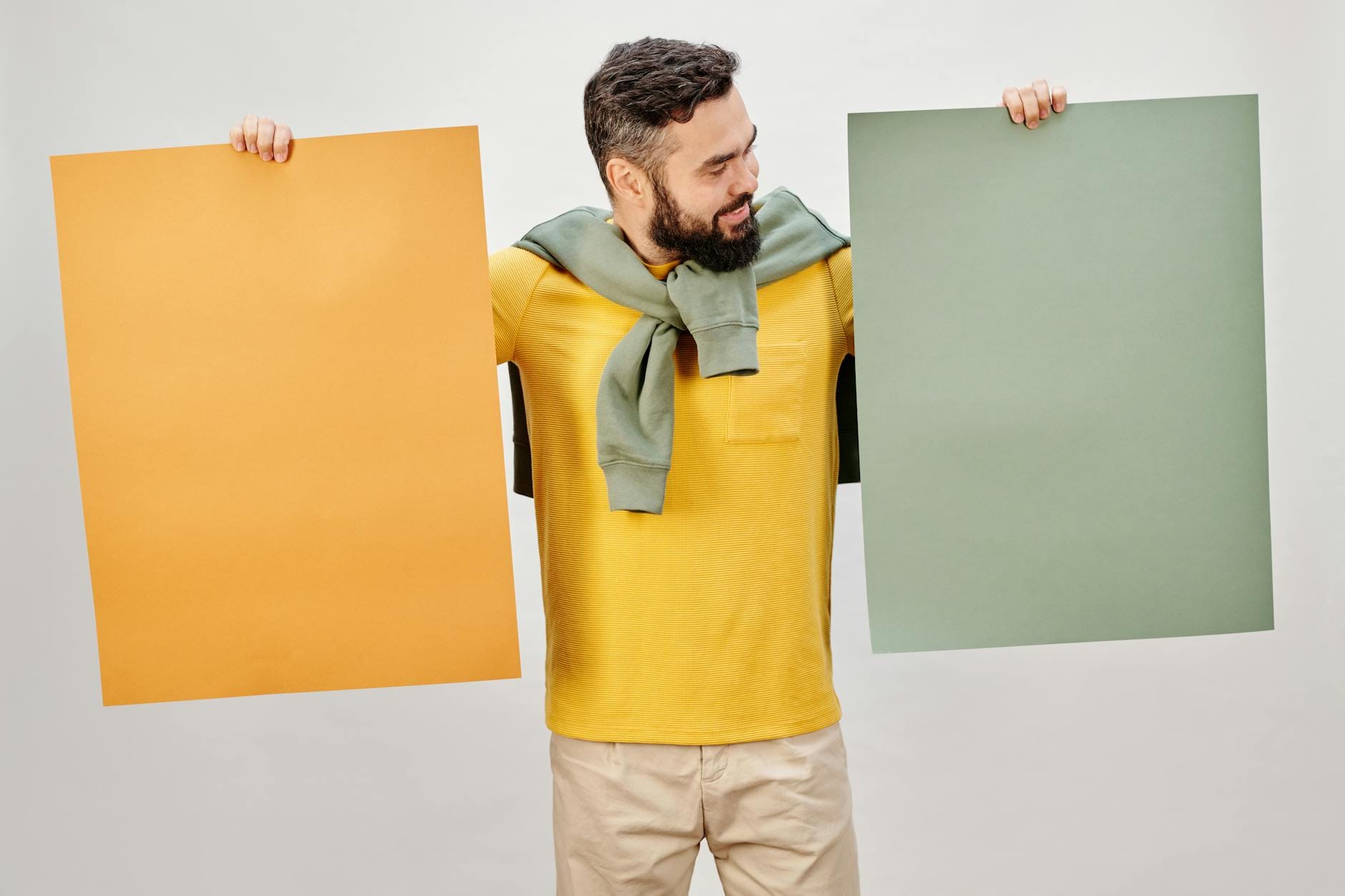 Mężczyzna w żółtej koszuli trzyma puste plakaty do projektu druku