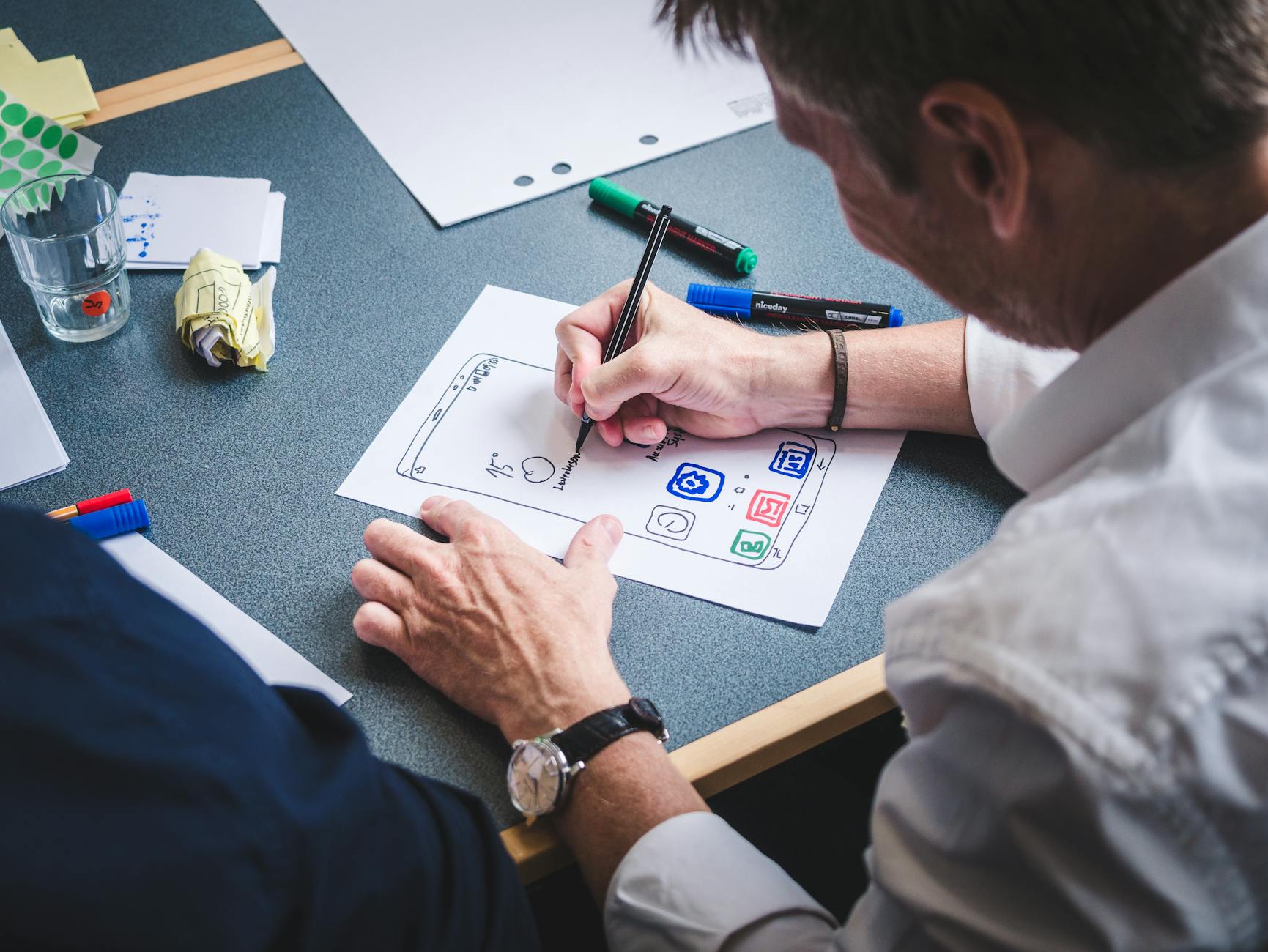 Projektant szkicuje papierowy prototyp aplikacji mobilnej przy biurku