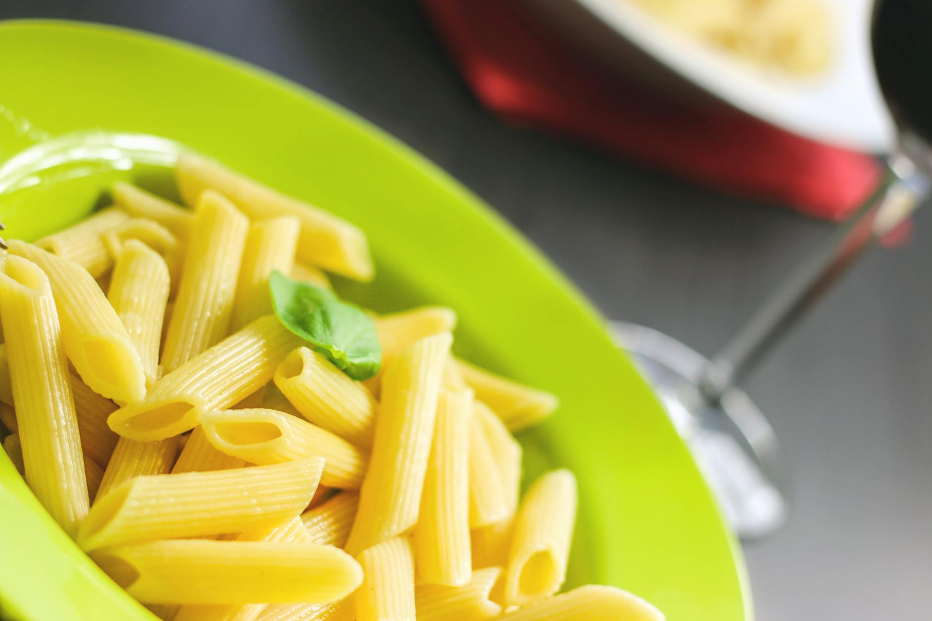 Makaron penne z bazylią na limonkowym talerzu z bliska