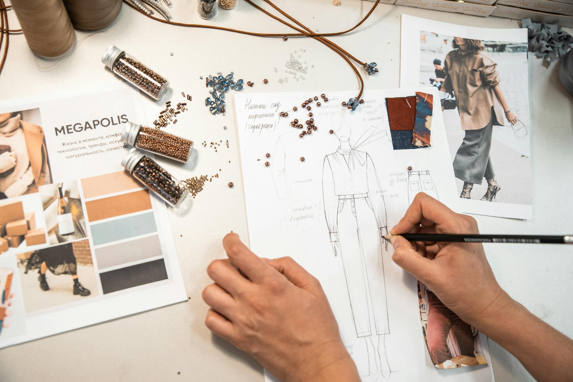 Projektant mody szkicuje przy biurku otoczonym materiałami i moodboardami
