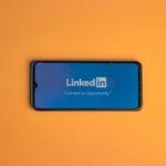 Smartfon z ekranem logowania LinkedIn na pomarańczowym tle