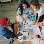 Zespół projektowy omawia plany architektoniczne w nowoczesnym biurze