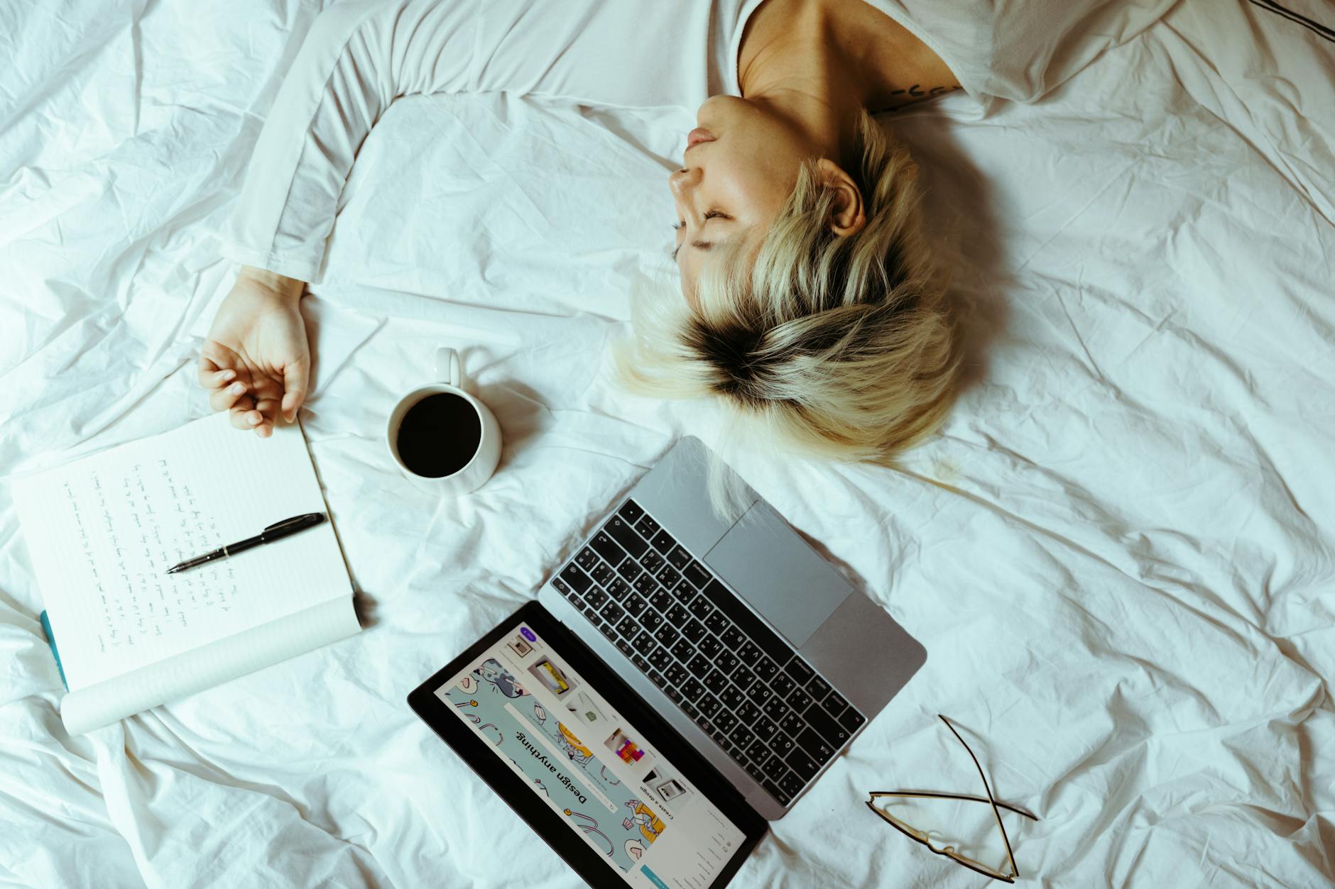 Zmęczona projektantka freelancerka śpi przy laptopie, notatniku i kawie