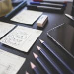 Biurko UX designera z planami interfejsu, smartfonem i przyborami biurowymi